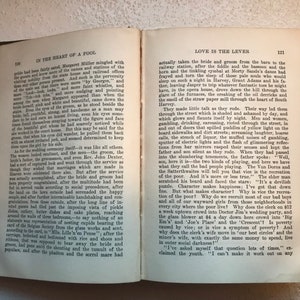 May include: An open book with a cream-colored cover and black text. The text on the left page reads "In the Heart of a Fool" and the text on the right page reads "Love is the Lever".