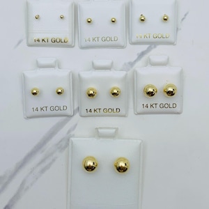 May include: A collection of gold stud earrings on white display cards. The earrings vary in size and shape, with the text "14 KT GOLD" printed on the cards. The bottom card reads "14KT. GOLD".