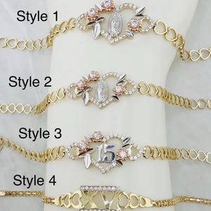 Könnte beinhalten: Vier goldfarbene Armbänder mit unterschiedlichen Designs. Die Stile 1 und 2 haben ein herzförmiges Mittelstück mit floralen Akzenten und einer religiösen Figur. Stil 3 hat ein Herz mit der Zahl "15". Stil 4 hat römische Ziffern. Der Text "Style 1", "Style 2", "Style 3" und "Style 4" sind sichtbar.