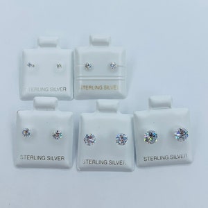 May include: Six pairs of sterling silver stud earrings with clear cubic zirconia stones. The earrings are displayed on white cards with the words "Sterling Silver" printed on them.