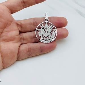 May include: Silver pendant necklace featuring a detailed five-pointed star design with intricate details and small clear stones.