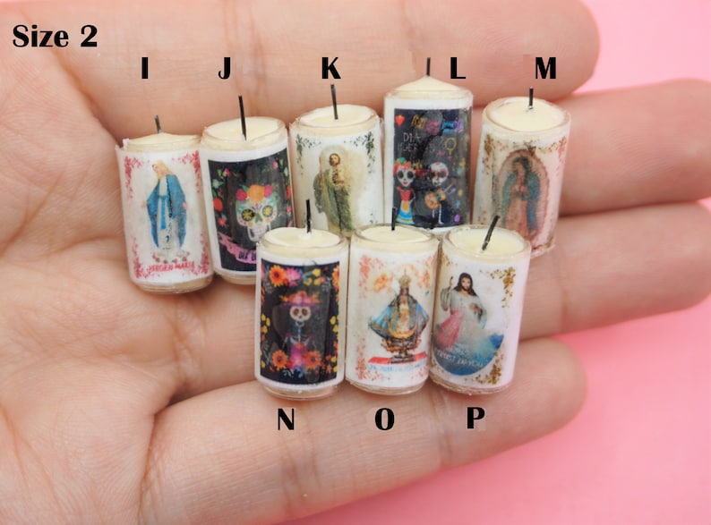 May include: A collection of eight miniature cylindrical candles labeled I through P, each featuring a unique religious or cultural graphic print. The candles are white with a single black wick and are arranged in a group, displaying various icons.