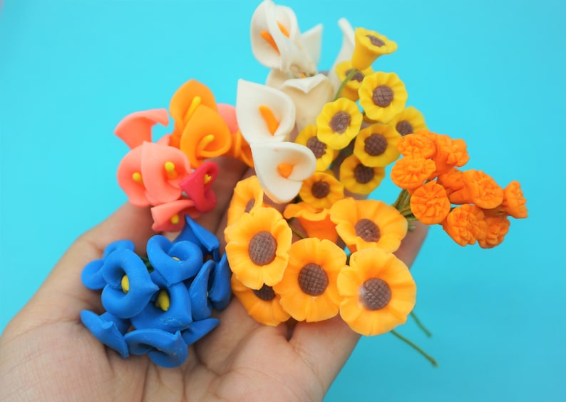 May include: A bouquet of colorful artificial flowers, including blue, orange, white, and yellow flowers. The flowers are made of a soft, pliable material and are perfect for adding a touch of color to any craft project.