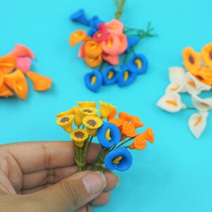 May include: Assortment of artificial flower bouquets in various colors, including yellow, orange, blue, white, and pink. The flowers are made of polymer clay and have a realistic appearance.