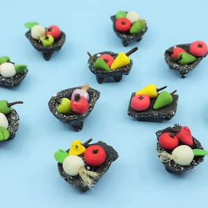 May include: Ten miniature black baskets filled with colorful vegetables, including red tomatoes, green peppers, yellow peppers, and white onions. The baskets are arranged on a light blue background.