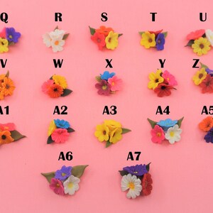 Pode incluir: Uma cole&ccedil;&atilde;o de pequenos arranjos florais coloridos sobre um fundo rosa. Cada arranjo apresenta uma variedade de tipos e cores de flores, incluindo amarelo, laranja, rosa, azul e branco. Os arranjos s&atilde;o rotulados com letras e n&uacute;meros.