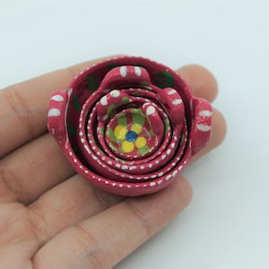 May include: A set of five nesting bowls, painted in a vibrant pink with white polka dots and green and yellow floral designs.