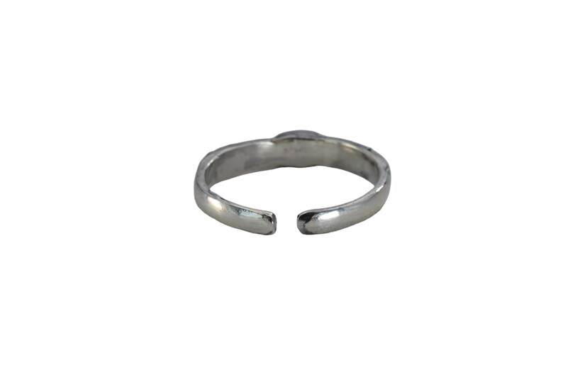 May include: A silver-colored adjustable ring with a simple design. The ring has a slightly textured surface and an open design, allowing for size adjustment. The ring is set against a white background.