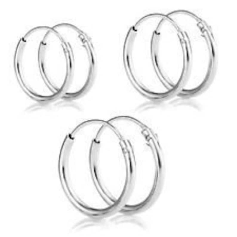 May include: Three pairs of silver hoop earrings. Each pair is a different size.