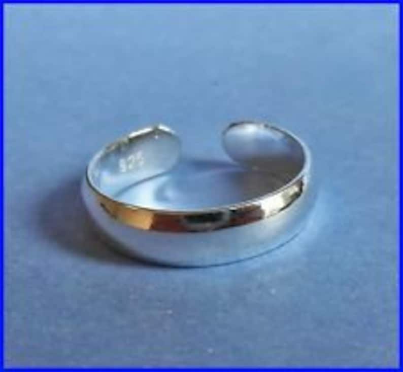 May include: A silver toe ring with a smooth, rounded surface. The ring is marked with "925" on the inside.