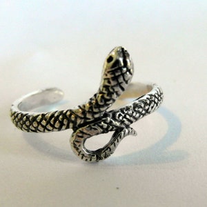 May include: A silver snake toe ring with a detailed, textured design. The snake is coiled with its head raised.
