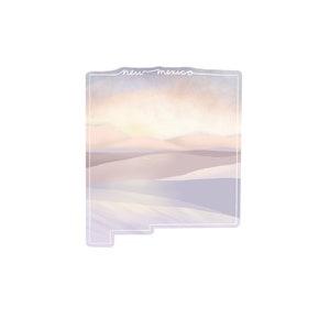 May include: A digital illustration of the state of New Mexico with a sunset over a desert landscape. The text "new mexico" is written in white cursive at the top of the image.
