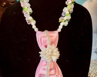 Splendido copricapo personalizzato con strass rosa e verdi e fiocco di perline abbinato. Un vero e proprio pezzo forte.