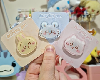 May include: Three acrylic pins with animal designs: a yellow bunny, a light blue bear, and a pink bear. Each pin is on a pastel backing card with the text "acrylic pin". The pins have a kawaii aesthetic.