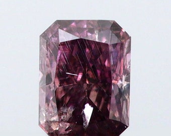 May include: A rectangular-cut, purplish-pink gemstone with a faceted surface. The gem has a high degree of clarity and brilliance, reflecting light to create a sparkling effect. The gemstone is set against a white background.