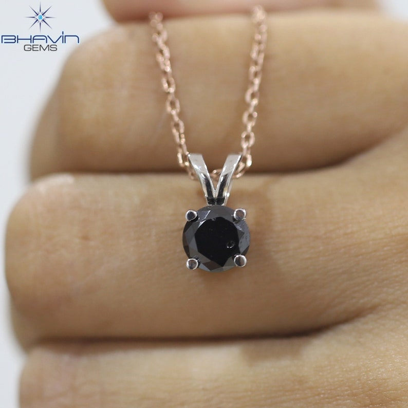 Pu&ograve; includere: Una collana con un ciondolo di diamante nero su una catena in oro rosa. Il diamante &egrave; incastonato in una montatura a griffe d'argento.
