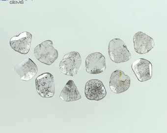 May include: A collection of twelve rough, clear, and grey diamonds of various shapes and sizes. The diamonds are arranged in a semi-circle on a white surface.