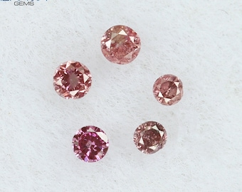 Puede incluir: Cinco diamantes rosas de diferentes tamaños sobre un fondo blanco. Los diamantes son redondos y tienen un corte brillante. Todos los diamantes están engastados en un engaste sencillo.