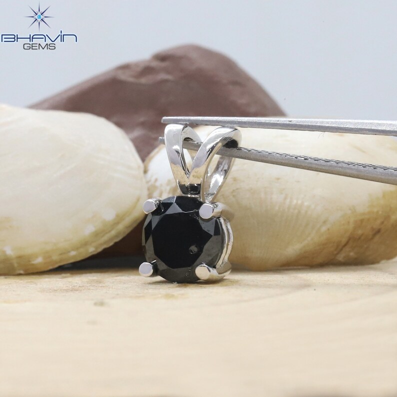 Pu&ograve; includere: Un ciondolo d'argento con una pietra preziosa nera. Il ciondolo &egrave; tenuto da una pinzetta.