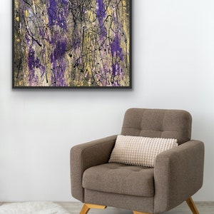 May include: Abstract art painting in a black frame. The artwork features purple, gold, and black colours in a drip-style design. The painting is displayed above a brown armchair with a cream-coloured pillow.