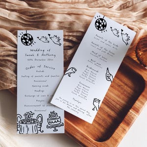 Könnte beinhalten: Zwei weiße Hochzeitskarten mit schwarzen Illustrationen einer Discokugel, Tauben, Kuchen und Tisch. Die Karten listen die Hochzeitsdetails und die Reihenfolge der Zeremonie auf.