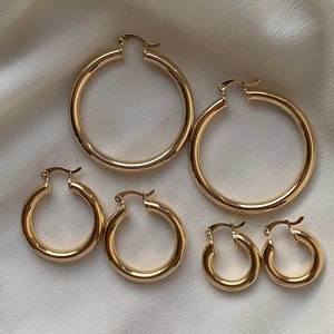 May include: Set of five gold hoop earrings of varying sizes. The largest hoop is about 2 inches in diameter, and the smallest hoop is about 1 inch in diameter.