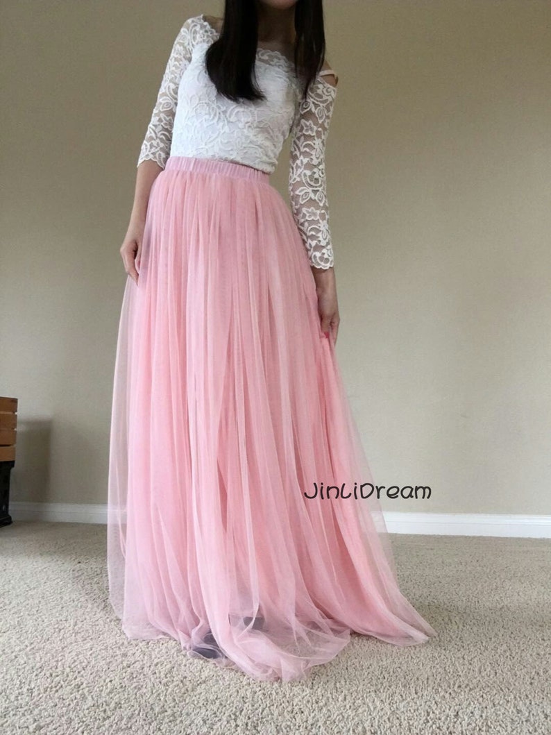 K&ouml;nnte beinhalten: Ein langer, rosa T&uuml;llrock mit einem wei&szlig;en Spitzenoberteil. Der Rock ist flie&szlig;end und hat einen weichen, zarten Look. Der Text "JinLiDream" ist auf dem Rock sichtbar.