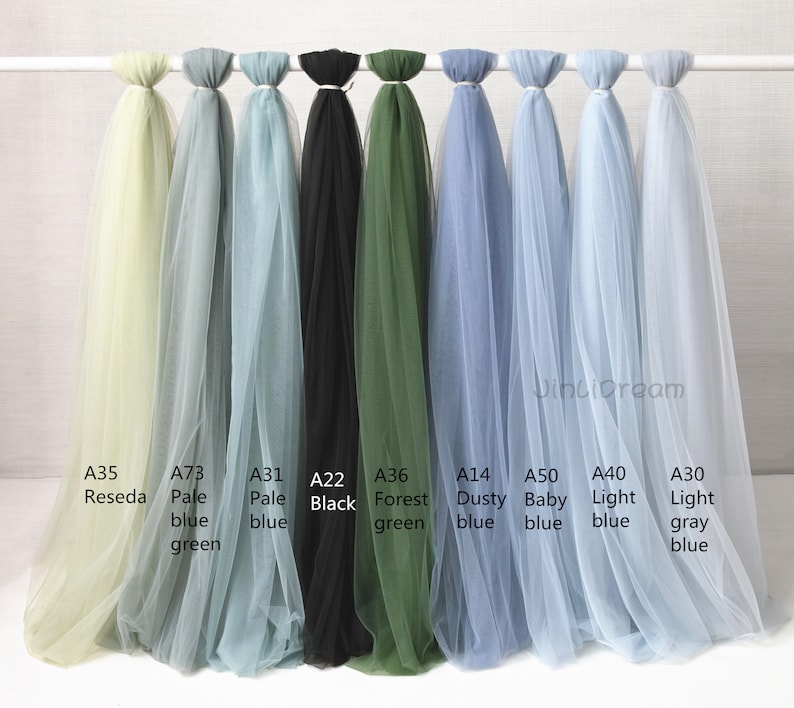 May include: Nine different colors of tulle fabric swatches, including pale blue, light gray, forest green, black, dusty blue, baby blue, light blue, pale green, and pale yellow.