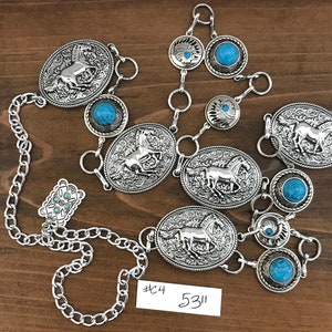 May include: A silver chain belt with turquoise stones and horse head charms. The belt is made of metal and has a silver finish. The belt is 53 inches long and has a #C4 tag.