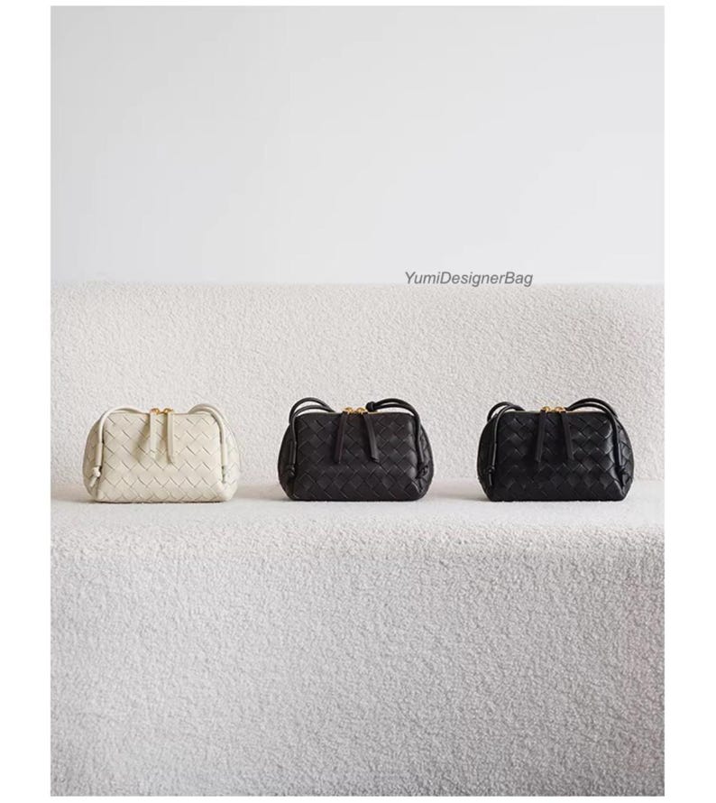 K&ouml;nnte beinhalten: Drei gewebte Lederhandtaschen in Creme und Schwarz. Die Taschen haben eine rechteckige Form mit abgerundeter Oberseite und einem goldfarbenen Rei&szlig;verschluss. Die Taschen werden auf einer wei&szlig;en, strukturierten Oberfl&auml;che pr&auml;sentiert. Der Text "YumiDesignerBag" ist sichtbar.