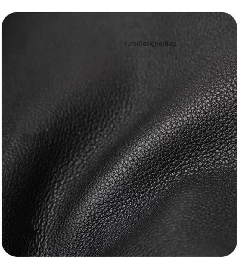 May include: Close-up of a black leather material with a textured surface. The leather has a natural grain and a matte finish. The image shows the details of the leather's texture and color.