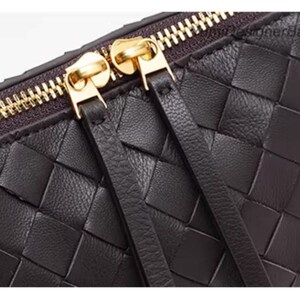 K&ouml;nnte beinhalten: Nahaufnahme einer dunkelbraunen Tasche aus geflochtenem Leder. Die Tasche hat einen goldenen Rei&szlig;verschluss und zwei goldene Rei&szlig;verschlusszipper. Das Leder ist in einem Flechtmuster gewebt. Die Tasche hat zwei Lederriemen, die am Rei&szlig;verschluss befestigt sind.