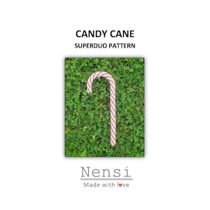 May include: A red and white candy cane on a green grassy background. The candy cane is a Superduo pattern. The text "Candy Cane Superduo Pattern" and "Nensi Made with love" is visible.