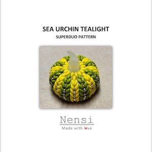 May include: A yellow and green beaded sea urchin tealight holder. The tealight holder is made with Superduo beads and has a silver accent. The tealight holder is a craft project by Nensi, made with love.