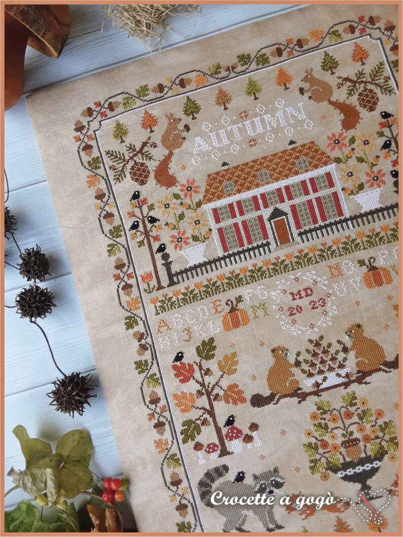 Peut inclure: Mod&egrave;le de point de croix repr&eacute;sentant une charmante sc&egrave;ne d'automne avec une maison, des arbres, des animaux et le mot "Automne". Le mod&egrave;le est con&ccedil;u par "Crocette a gogo".