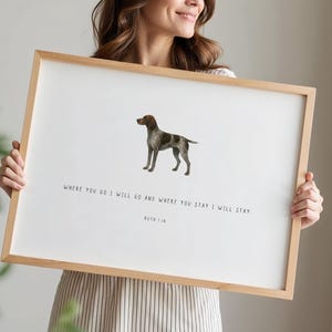 May include: A framed print with a dog illustration in brown and grey. The artwork displays the text "WHERE YOU GO I WILL GO AND WHERE YOU STAY I WILL STAY. RUTH 1:16". The frame is made of light-coloured wood, suitable for home decor.