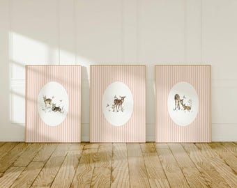 May include: Three framed prints with pink and white striped backgrounds. Each print features a circular design with a watercolour illustration of a deer in a woodland setting.