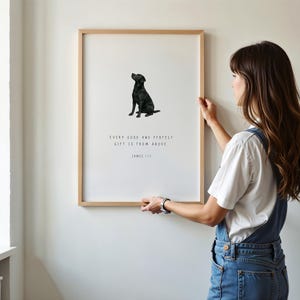 Może przedstawiać: Oprawiony wydruk z ilustracją czarnego labradora. Wydruk zawiera cytat "EVERY GOOD AND PERFECT GIFT IS FROM ABOVE" i nazwisko "JAMES 1:17". Grafika jest wyświetlana na białej ścianie.
