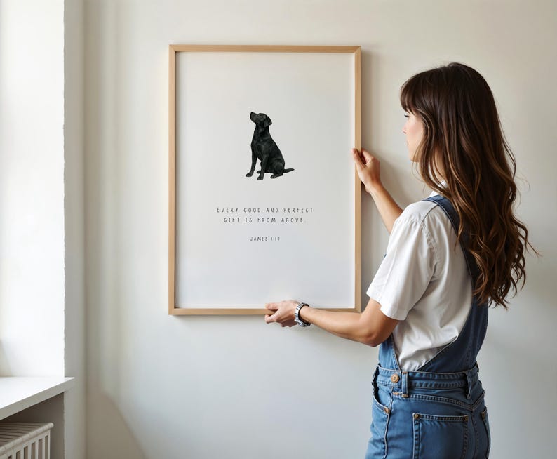 Może przedstawiać: Oprawiony wydruk z ilustracją czarnego labradora. Wydruk zawiera cytat "EVERY GOOD AND PERFECT GIFT IS FROM ABOVE" i nazwisko "JAMES 1:17". Grafika jest wyświetlana na białej ścianie.