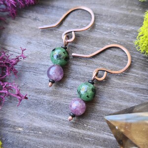 May include: A pair of earrings with green and purple gemstone beads and rose gold hooks.