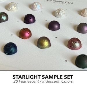 May include: A Starlight Sample Card featuring 20 dome-shaped paint samples in various pearlescent and iridescent colors. Each sample is numbered on a white background, displaying shades of blue, purple, gold, pink, and white with metallic finishes.