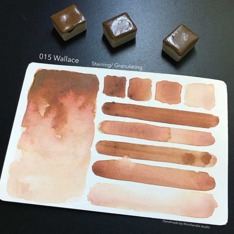 Puede incluir: Una paleta de pintura acuarela etiquetada como "015 Wallace" con una descripci&oacute;n de "Staining/Granulating". La paleta se muestra con varias muestras del color, que van del marr&oacute;n claro al marr&oacute;n oscuro.