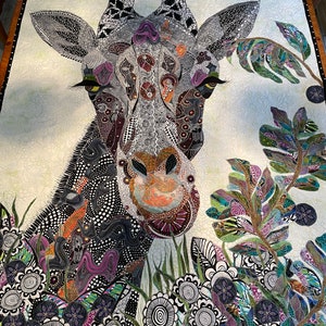 May include: A close-up of a colorful, patterned quilt featuring a giraffe's head and neck. The giraffe is surrounded by a variety of flowers and leaves, all in a similar style. The quilt is made of fabric scraps and is a unique and creative piece of art.
