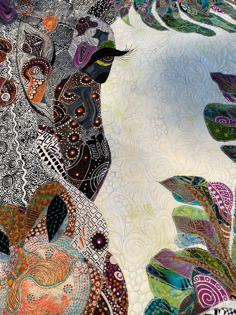 May include: A close-up of a colorful quilt with a detailed design of an eye and leaves. The quilt is made of various fabrics and textures, including patterned and solid fabrics. The eye is surrounded by intricate details, including swirls and dots. The leaves are green, brown, and purple.