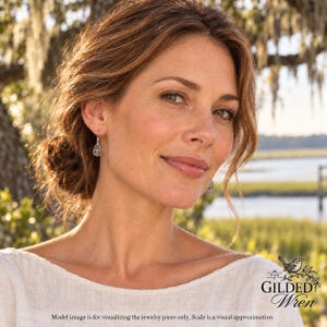 May include: A pair of silver drop earrings featuring a delicate, openwork filigree pattern in a teardrop shape. The earrings hang from simple silver hooks and are worn on the earlobes. The design is intricate, showcasing a fine metal lattice.