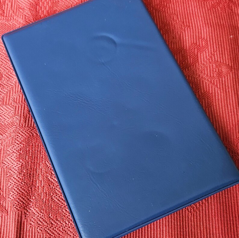 May include: A dark blue leather-bound journal or notebook with a smooth, textured surface.