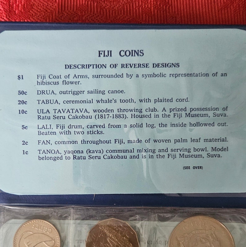 May include: A close-up of a display showing the reverse designs of Fiji coins. The display includes a description of each coin, including its denomination, name, and a brief description of the design. The coins are arranged in a row, with the largest coin on the left and the smallest coin on the right.