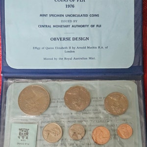 May include: A blue coin collection case with a clear plastic window showing a set of 1976 Fiji coins. The case has a label that reads "Coins of Fiji 1976" and "Mint Specimen Uncirculated Coins".