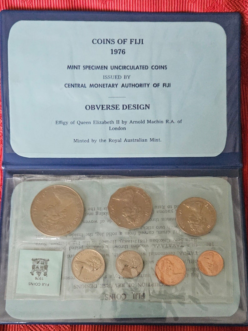 May include: A blue coin collection case with a clear plastic window showing a set of 1976 Fiji coins. The case has a label that reads "Coins of Fiji 1976" and "Mint Specimen Uncirculated Coins".