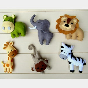 Könnte beinhalten: Ein Set aus sechs Filztieren, darunter ein grünes Flusspferd, ein grauer Elefant, ein brauner Löwe, eine gelbe Giraffe, ein brauner Affe und ein schwarz-weißes Zebra.
